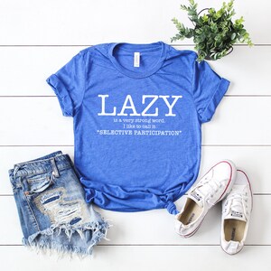 Op de afbeelding: Een blauw T-shirt met de tekst "LAZY is a very strong word. I like to call it "SELECTIVE PARTICIPATION""