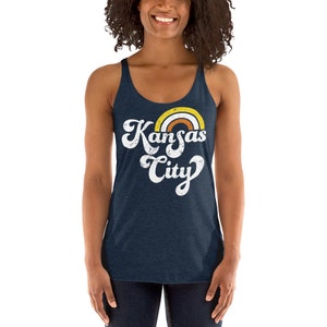 Puede incluir: Un top de tirantes azul marino con un gr&aacute;fico blanco desgastado que dice "Kansas City" con un arco&iacute;ris sobre el texto.