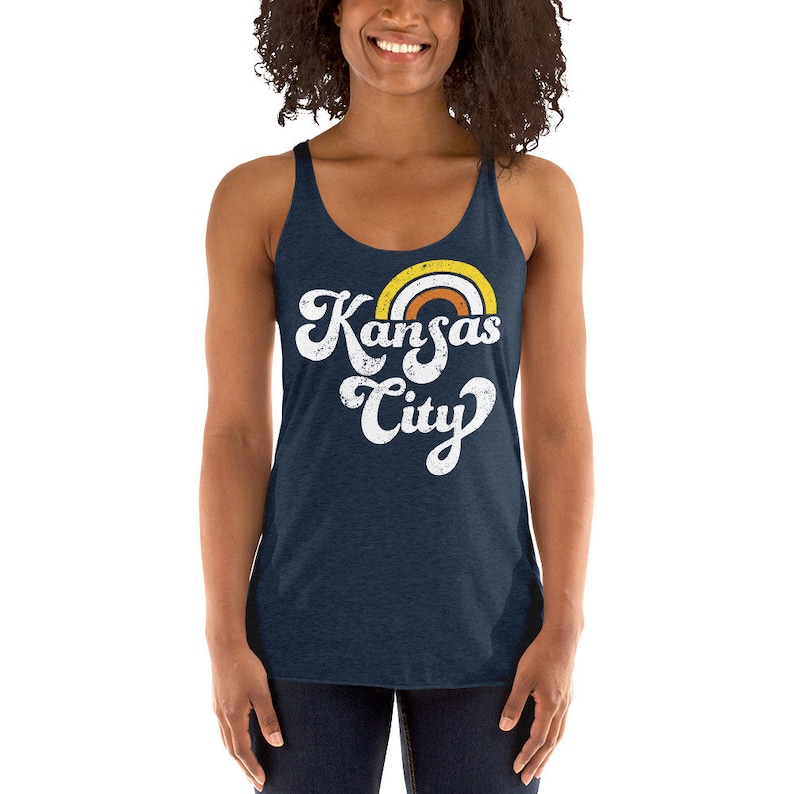 Puede incluir: Un top de tirantes azul marino con un gr&aacute;fico blanco desgastado que dice "Kansas City" con un arco&iacute;ris sobre el texto.