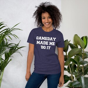 May include: A navy blue t-shirt with a white distressed graphic that reads "GAMEDAY MADE ME DO IT".