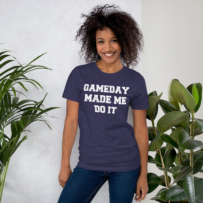 May include: A navy blue t-shirt with a white distressed graphic that reads "GAMEDAY MADE ME DO IT".