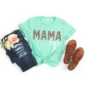 May include: A mint green t-shirt with the words "MAMA life" printed on it. The word "MAMA" is in leopard print.