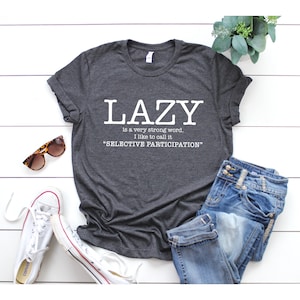 Op de afbeelding: Grijs T-shirt met witte tekst die luidt: "LAZY is a very strong word. I like to call it "SELECTIVE PARTICIPATION""