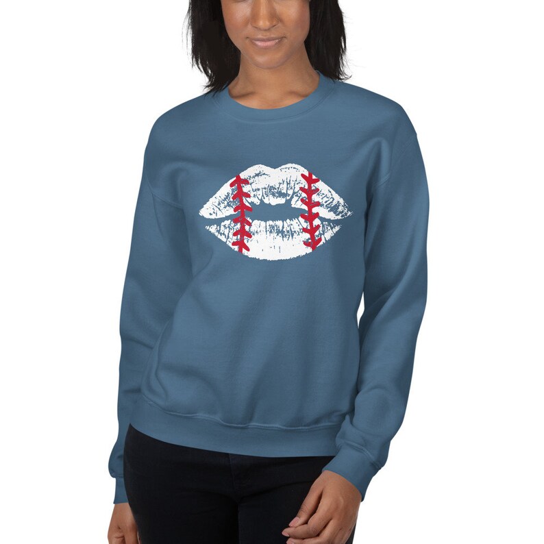 May include: A blue sweatshirt with a white baseball-themed lips design. The lips are outlined in red stitching.