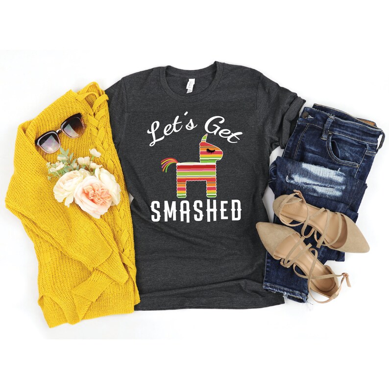 May include: A dark heather grey t-shirt with a white graphic of a pinata and the text "Let's Get Smashed".