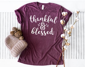 Puede incluir: Una camiseta color granate con el texto "thankful & blessed" en letras blancas.