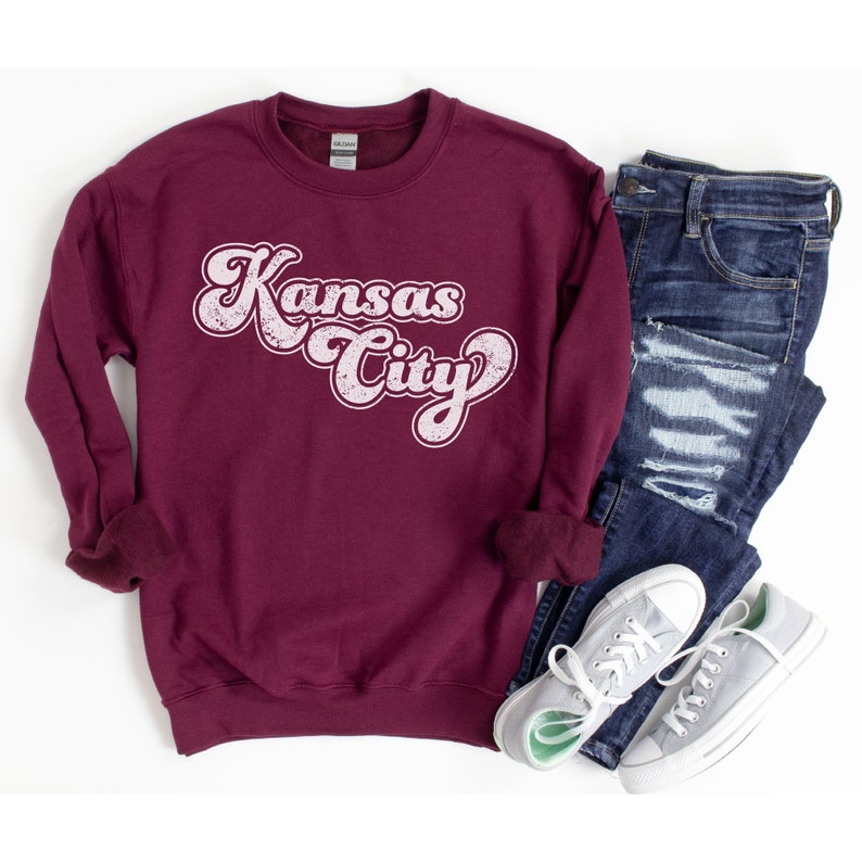 May include: A maroon sweatshirt with a white vintage-style graphic that says "Kansas City".