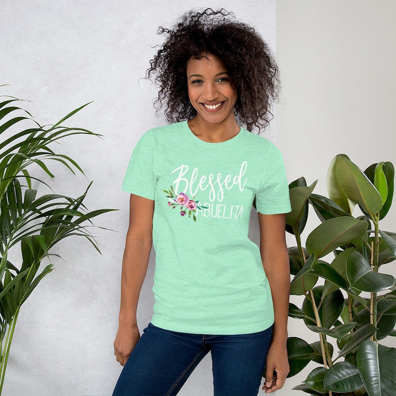 May include: A light green t-shirt with the text "Blessed Abuelita" in white lettering with a floral design.