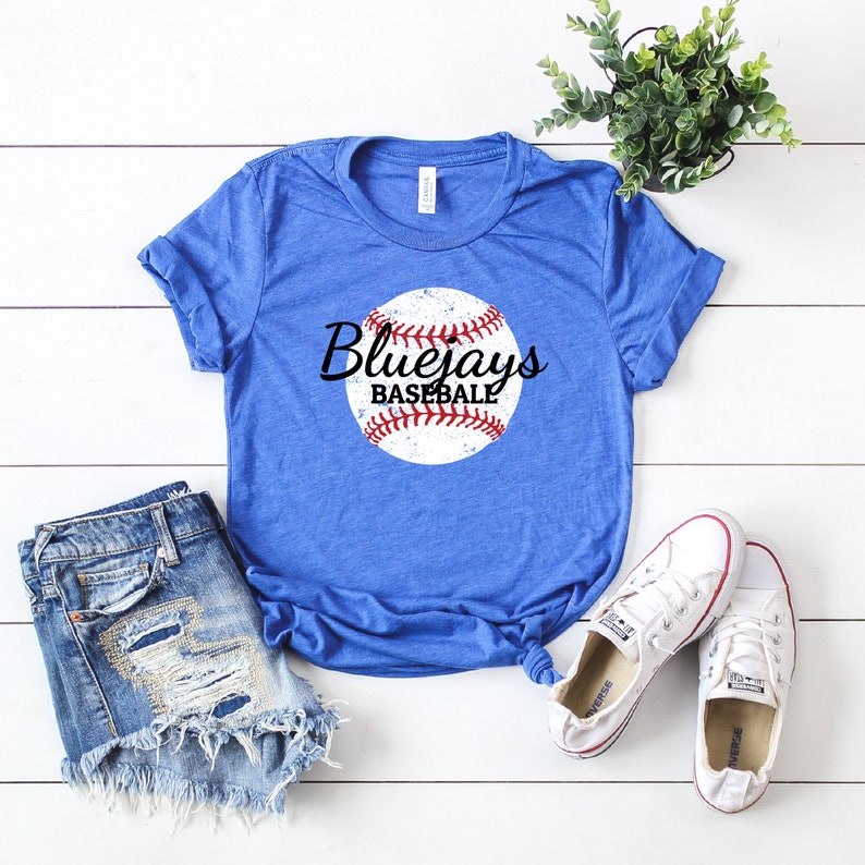 May include: A royal blue t-shirt with a distressed white baseball graphic and the text "Bluejays Baseball" in black cursive lettering.