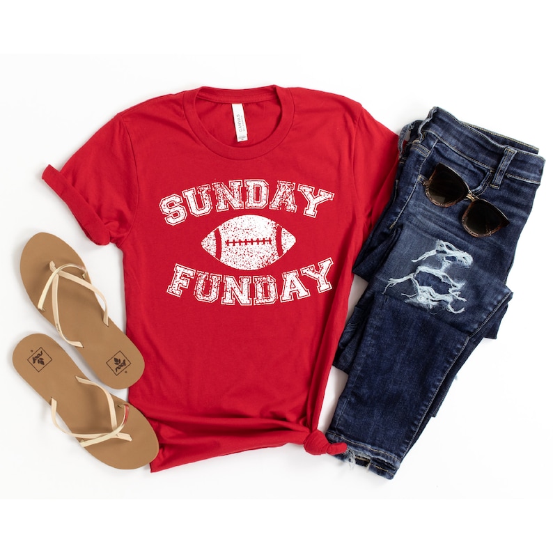 Op de afbeelding: Rood T-shirt met een witte afbeelding van een voetbal en de tekst "SUNDAY FUNDAY".