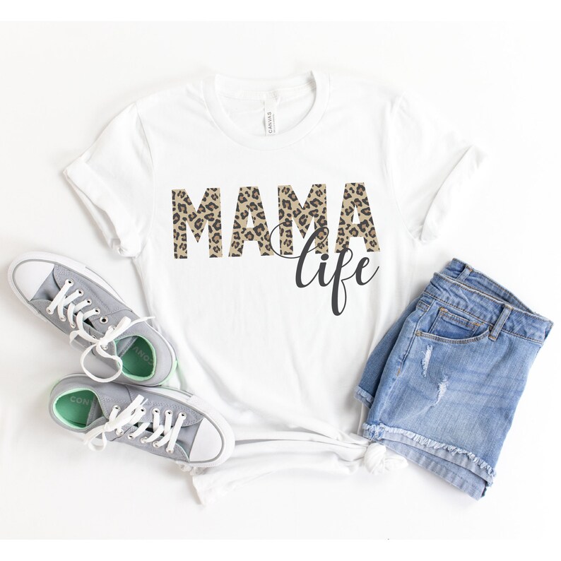 May include: White t-shirt with the text "Mama life" in black lettering. The word "Mama" is printed in a leopard print pattern.