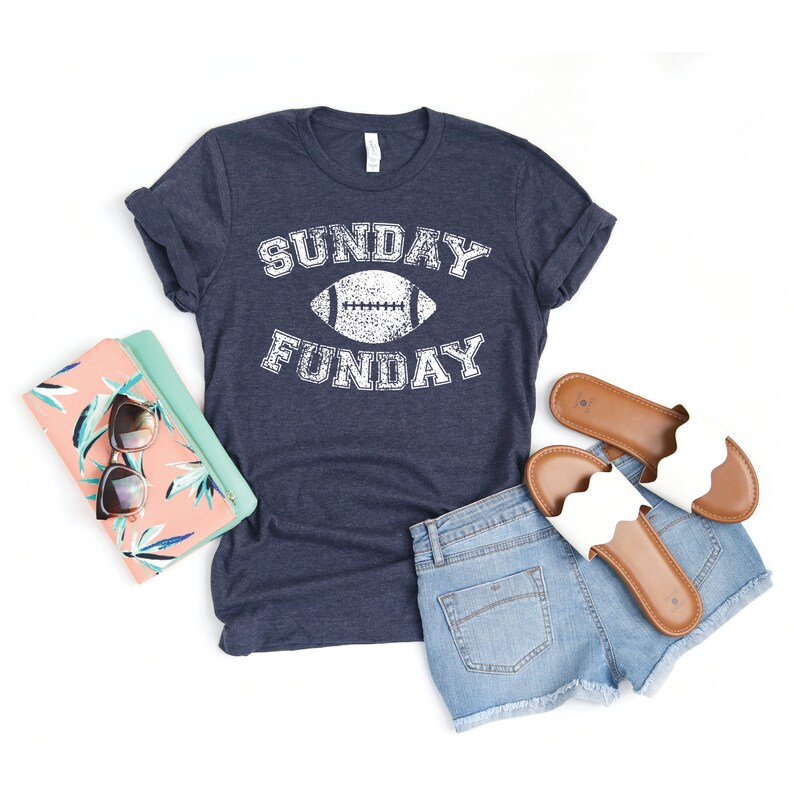 Op de afbeelding: Een marineblauw t-shirt met een witte, verweerde afbeelding van een voetbal en de tekst "SUNDAY FUNDAY".