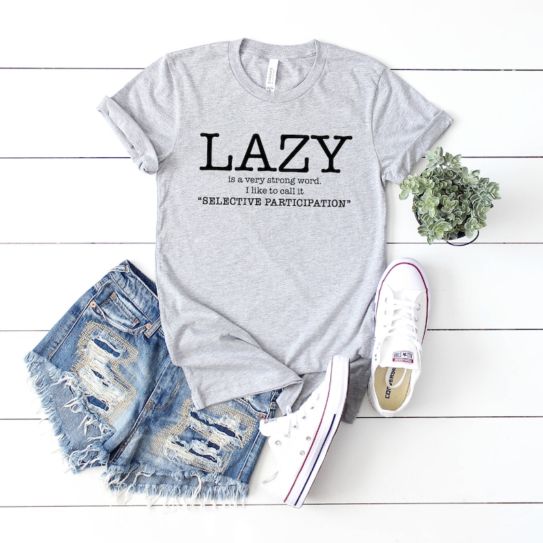 Op de afbeelding: Grijs T-shirt met de tekst "LAZY is a very strong word. I like to call it "SELECTIVE PARTICIPATION""