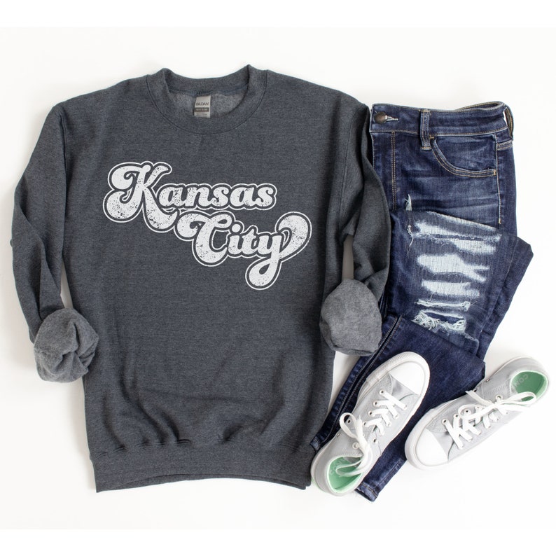 May include: A dark gray sweatshirt with a white vintage-style graphic that says "Kansas City".