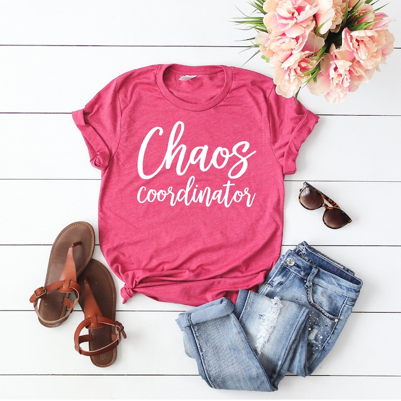以下が含まれることがあります： 白い文字で「Chaos coordinator」と書かれたピンクのTシャツ