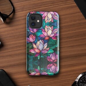 May include: A smartphone case featuring a stained glass pattern of pink and white lotus flowers with green leaves against a dark blue background. The design covers the entire back of the case, including the area around the dual camera lens.