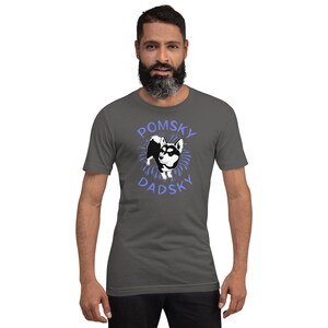 May include: A dark gray t-shirt with a cartoon image of a Pomsky dog in a blue circle with the text "Pomsky Dadsky" in blue.