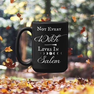 May include: Black ceramic coffee mug with white text that reads "Not Every Witch Lives In Salem" with a broom and moon phases graphic.