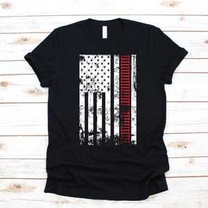 May include: Black t-shirt with a distressed American flag design featuring a red railway track down the centre.