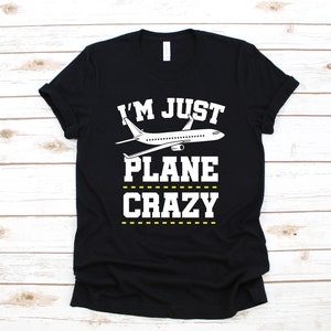 May include: Black t-shirt with white text that reads "I'm Just Plane Crazy" and a white airplane graphic.