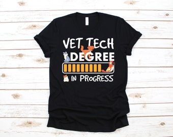 Puede incluir: Camiseta negra con el texto blanco "VET TECH DEGREE IN PROGRESS". El diseño incluye ilustraciones de un gato, un perro, un hámster y un loro, junto con una barra de progreso.