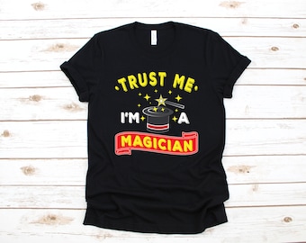 May include: Black t-shirt with a white graphic that says "Trust me, I'm a magician" with a black top hat and a magic wand with stars.