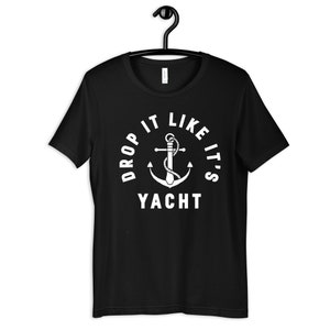 Op de afbeelding: Zwart T-shirt met een witte anker en de tekst "Drop it like it's Yacht" in een cirkel.