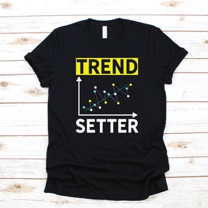 Puede incluir: Camiseta negra con un gráfico blanco de un gráfico de líneas con el texto "TREND SETTER" en amarillo y blanco.