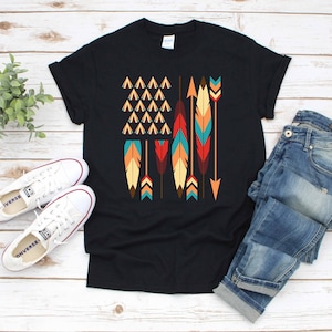May include: A black t-shirt with a graphic of an American flag made of colorful feathers and arrows. The flag is centered on the shirt.