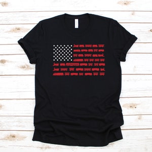 May include: Black t-shirt featuring a red, white and blue American flag design made of train carriages.