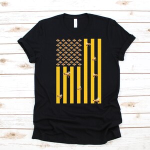 May include: A black t-shirt with a yellow and black bee design that resembles the American flag.