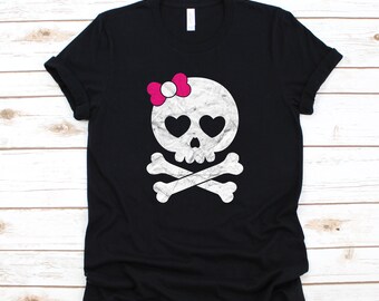 May include: Black t-shirt with a white skull and crossbones design. The skull has pink hearts for eyes and a pink bow on top.