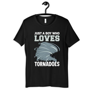 Puede incluir: Camiseta negra con un gráfico blanco de un tornado y el texto "Just a boy who loves tornadoes".