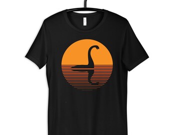 May include: Black t-shirt with a graphic of a silhouette of the Loch Ness Monster in a retro sunset design.