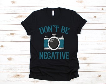 May include: Black t-shirt with a teal blue graphic of a camera and the text "Don't be negative".