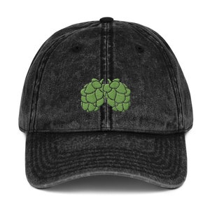 May include: A black vintage washed denim baseball cap with an embroidered green hop cone design.