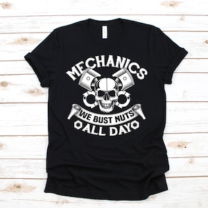 May include: Black t-shirt featuring a white skull and crossed pistons graphic. The text "Mechanics We Bust Nuts All Dayo" is printed below the graphic.