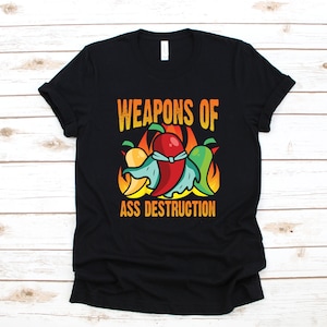 Może przedstawiać: Czarny T-shirt z grafiką papryczek chili i tekstem "Weapons of Ass Destruction".