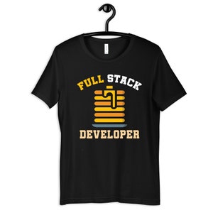 May include: Black t-shirt with white text that reads "Full Stack Developer". A cartoon image of a stack of pancakes with syrup is in the center of the text.