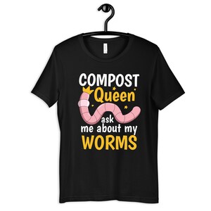 Op de afbeelding: Zwart T-shirt met een roze worm die een gouden kroon draagt en de tekst "COMPOST Queen" en "ask me about my WORMS".