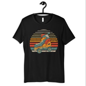 Może przedstawiać: Czarny T-shirt z grafiką w stylu vintage przedstawiającą rolkę przed zachodem słońca. Rolka jest niebieska, żółta i pomarańczowa. Zachód słońca jest czerwony, pomarańczowy i żółty.