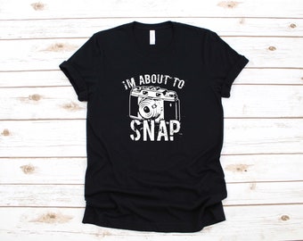 May include: Black t-shirt with a white graphic of a vintage camera and the text "I'm about to snap".