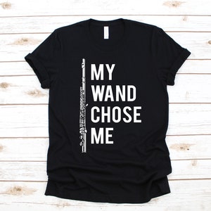 Puede incluir: Camiseta negra con un gráfico blanco de una flauta y el texto "My Wand Chose Me."