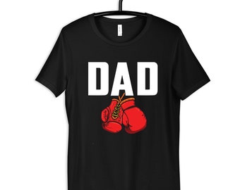 May include: Black t-shirt with the word "DAD" in white letters and a pair of red boxing gloves hanging below.