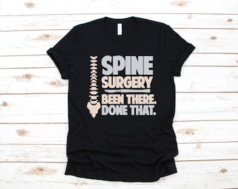 May include: Black t-shirt with a white spine graphic and the text "SPINE SURGERY BEEN THERE. DONE THAT."