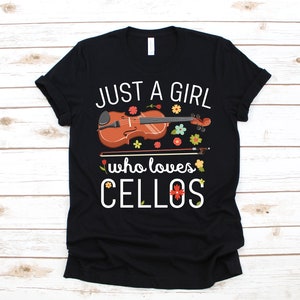 以下が含まれることがあります： 白い文字で「Just a girl who loves cellos」と書かれた黒いTシャツ。テキストの上に、花柄の装飾が施された茶色のチェロが描かれています。