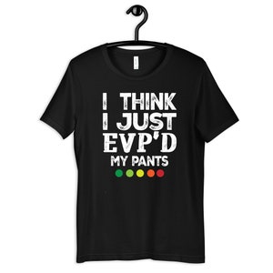 May include: Black t-shirt with white text that reads "I think I just EVP'd my pants" and a row of five coloured dots below the text. The dots are green, yellow, orange, and red.