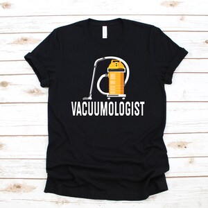 Puede incluir: Camiseta negra con un gráfico blanco de una aspiradora amarilla y el texto "VACUUMOLOGIST".