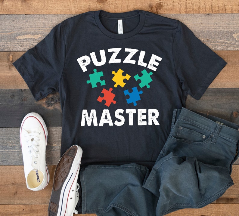 May include: A black t-shirt with the text "PUZZLE MASTER" in white with a graphic of five colorful puzzle pieces.