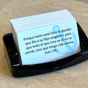 Op de afbeelding: Een stapel witte kaarten met een blauw anker en de tekst "Porque tanto am&oacute; Dios al mundo que dio a su Hijo unig&eacute;nito, para que todo el que cree en &eacute;l no se pierda, sino que tenga vida eterna. Juan 3:16" in het Spaans.